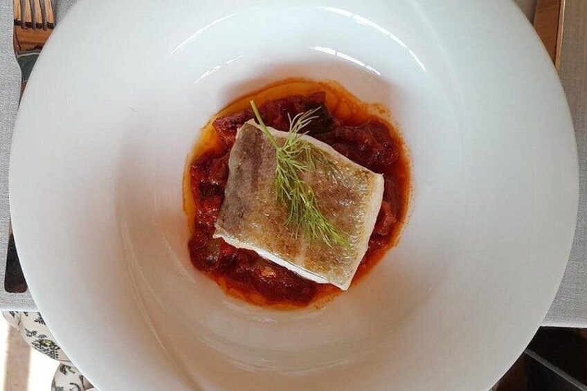 Un cuenco blanco con un trozo de pescado, adornado con eneldo. 2