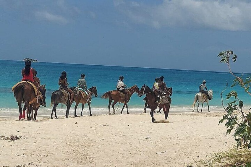 People riding horses on a beach with the ocean in the background. 2