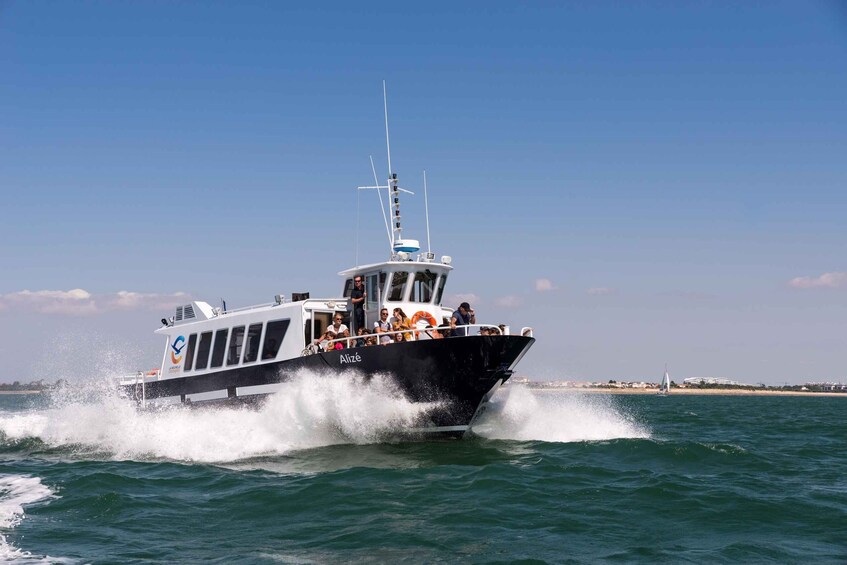 A black and white boat with passengers, moving through choppy water. 1
