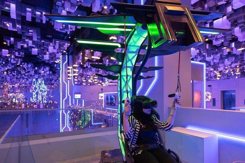 En person med VR-briller holder VR-controllere i et futuristisk indendørsmiljø med neonbelysning og geometriske former. 1