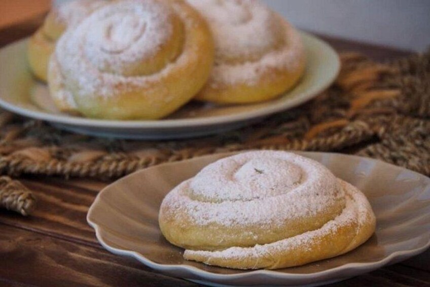 A plate with a pastry dusted with powdered sugar, placed on a woven mat. 2