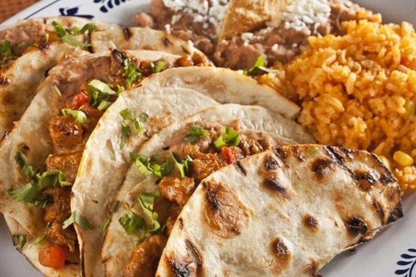 A plate of food with tacos, rice, and beans. 4