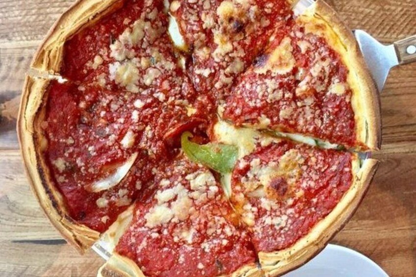 A deep-dish pizza with toppings, served on a wooden table. 3