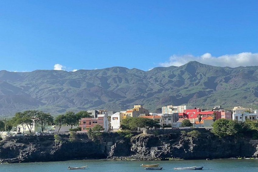 A coastal town with colorful buildings, boats on the water, and mountains in the background. 4