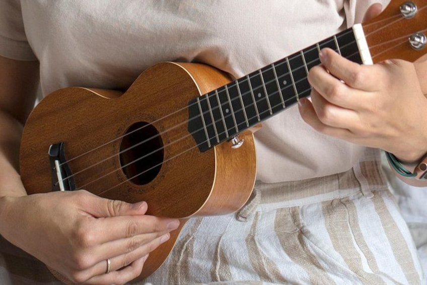 A person holding a ukulele, wearing a light-colored shirt and striped pants. 2