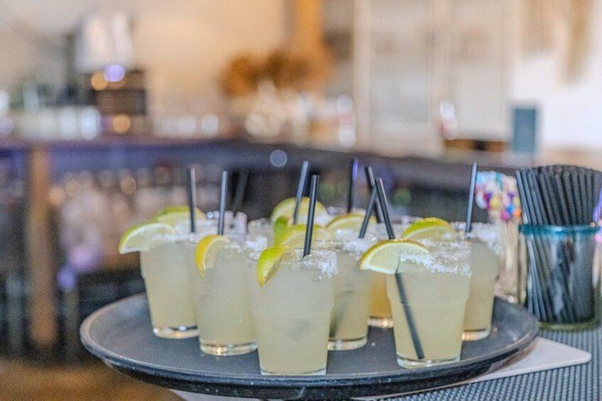 A tray of drinks with straws and lime wedges. 2