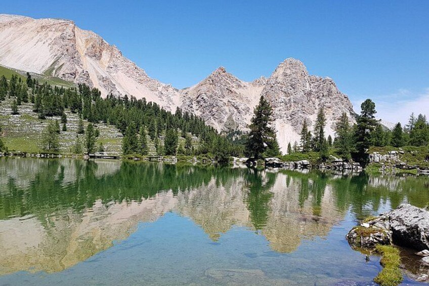 A mountain lake with clear reflections, surrounded by rocky mountains and dense forests. 1