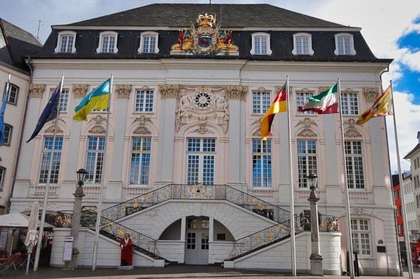 A grand building with a clock tower, multiple flags, and a staircase leading to the entrance. 3