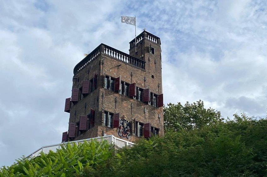 A multi-story tower with a flag, surrounded by greenery. 2