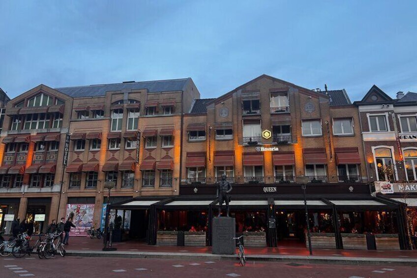 A multi-story building with a Bavarian sign, a Queen's sign, and a NAK restaurant. 1