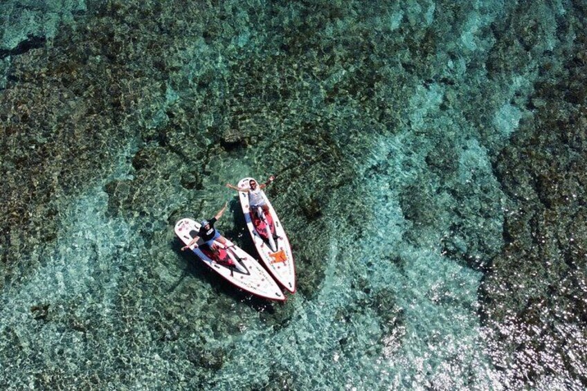 Two people paddling kayaks on clear turquoise water. 5