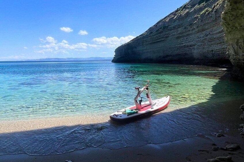 A kayak on a beach with clear water and a rocky cliff. 1