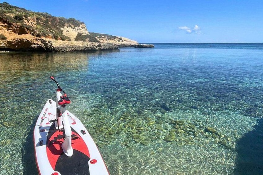 A kayak on a clear, shallow body of water with rocky terrain and cliffs in the background. 4