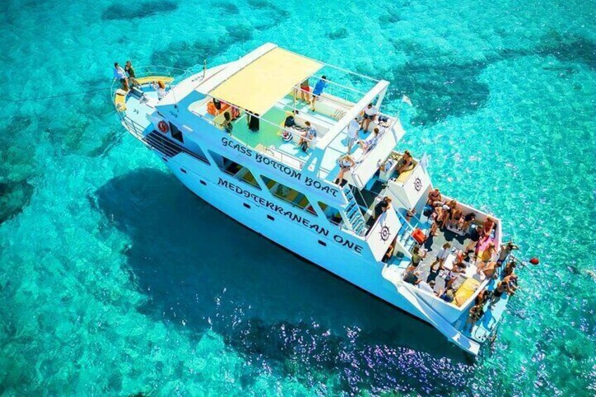 A boat named 'Glass Bottom Boat' with people on deck, surrounded by clear turquoise water. 3