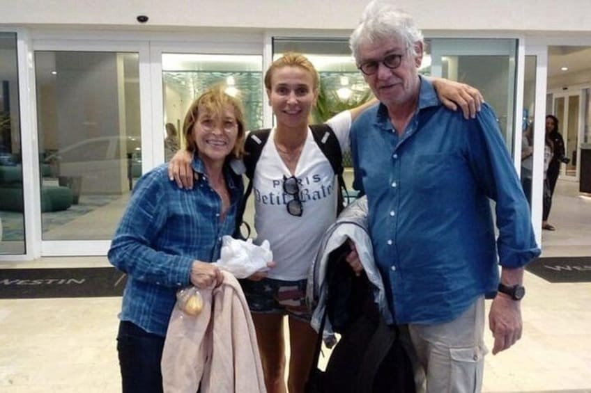 Tres personas de pie en un espacio interior con un muro de cristal y una puerta al fondo. 3