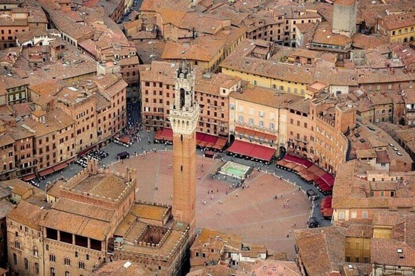 An aerial view of a historic city center with a prominent square, a tall tower, and surrounding buildings. 3