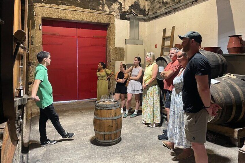 A group of people standing in an outdoor area with barrels and a red door. 3