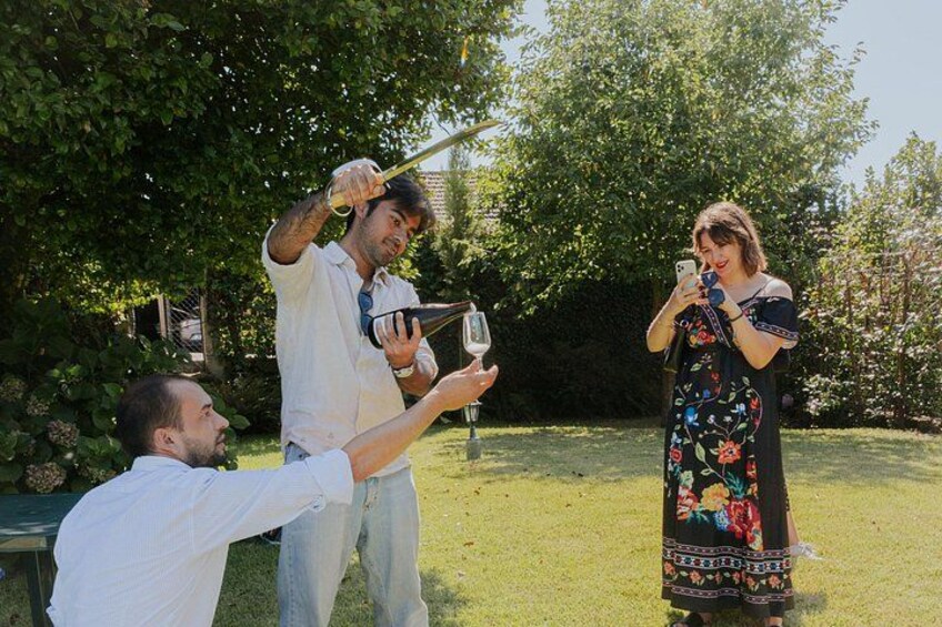Three people outdoors, one holding a camera, another holding a wine glass, and a third taking a photo. 5