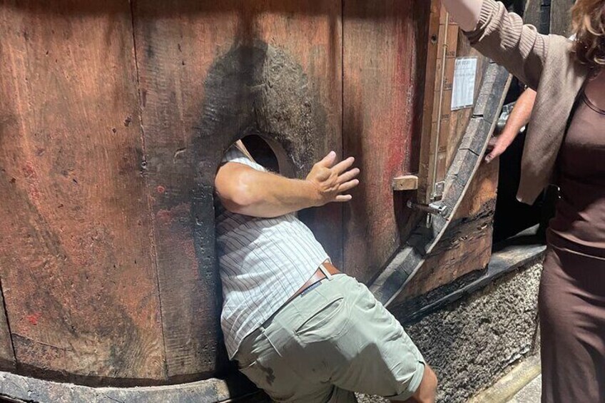 A man leaning against a wooden structure with a circular opening. 2