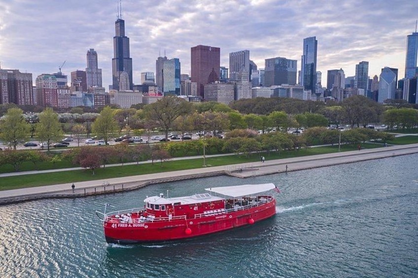 A red boat on a river with a city skyline in the background. 5