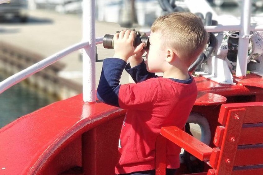 A child looking through binoculars on a red boat. 4