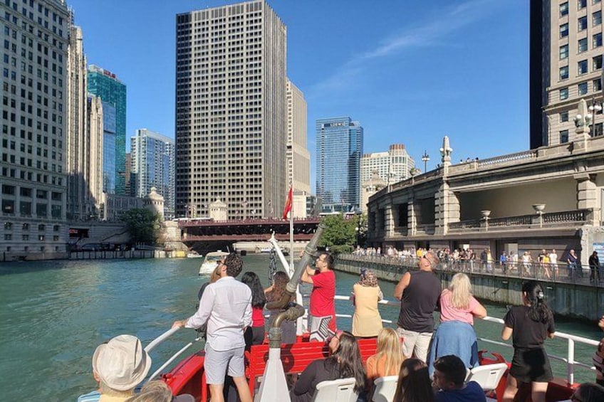 A boat tour with passengers enjoying the view of a city skyline and river. 3