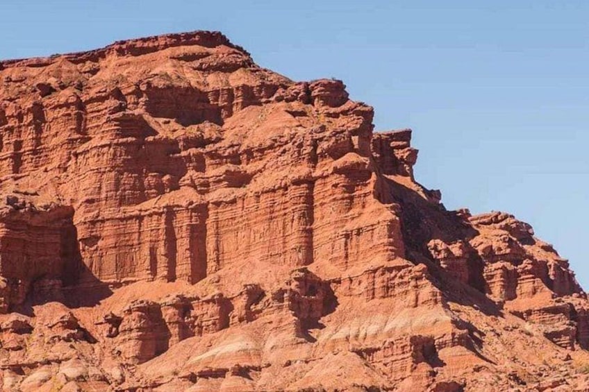 Eine große rote Felsformation mit schichtweiser Gesteinsbildung und blauem Himmel. 2