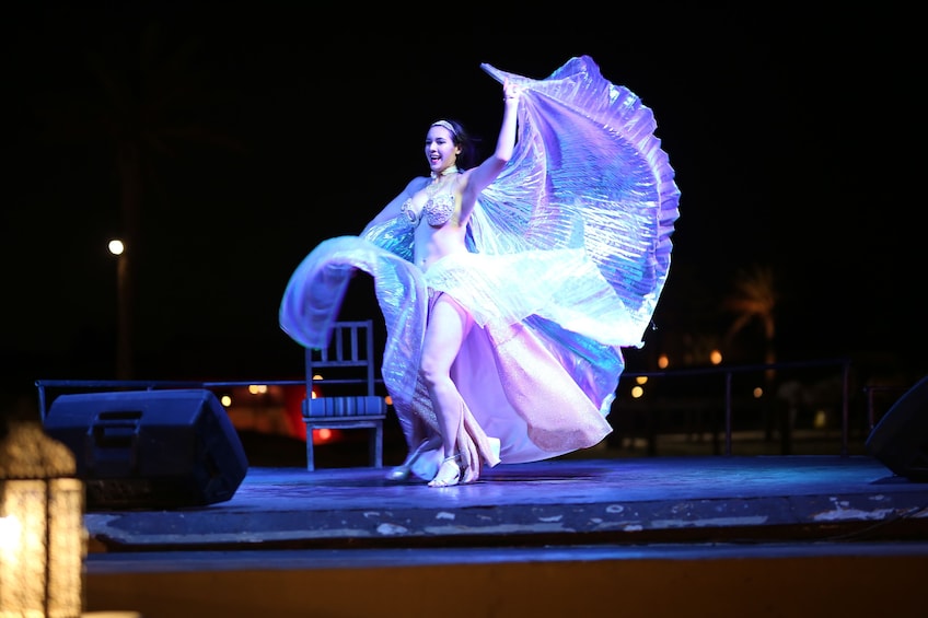 Una persona bailando en un escenario con un traje vaporoso y translúcido. 4