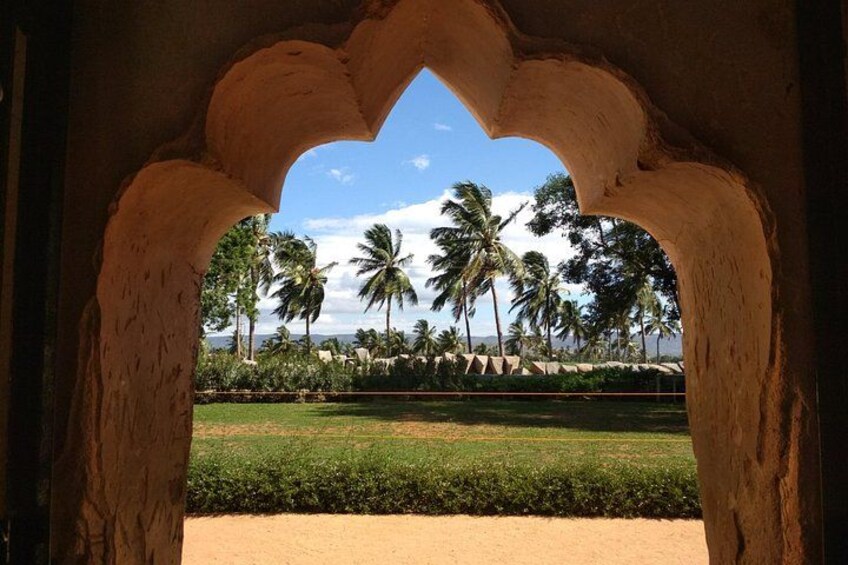 A view through an archway with palm trees and a clear sky. 1
