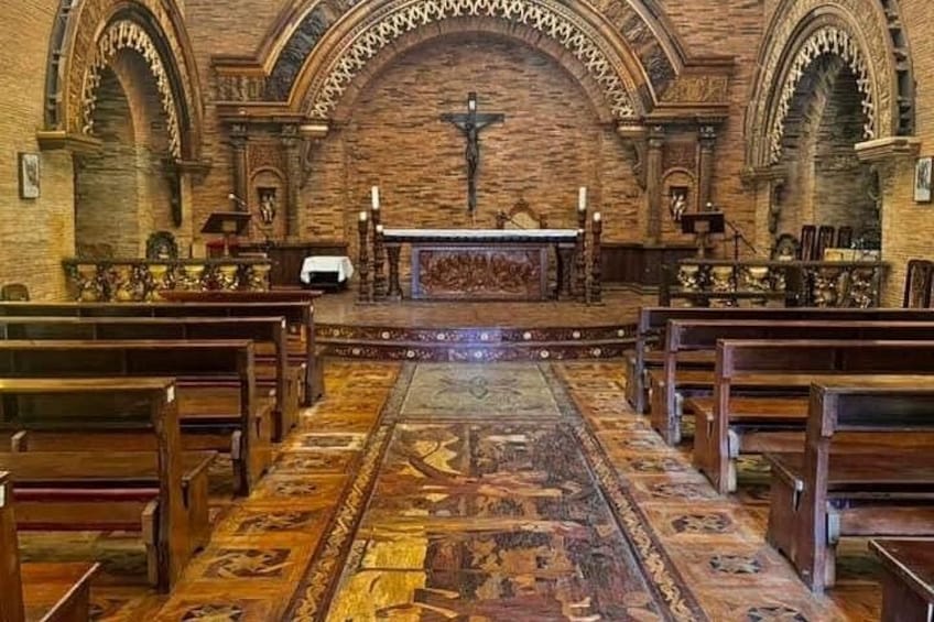 An interior of a church with wooden pews, a central altar, and a patterned carpet. 4