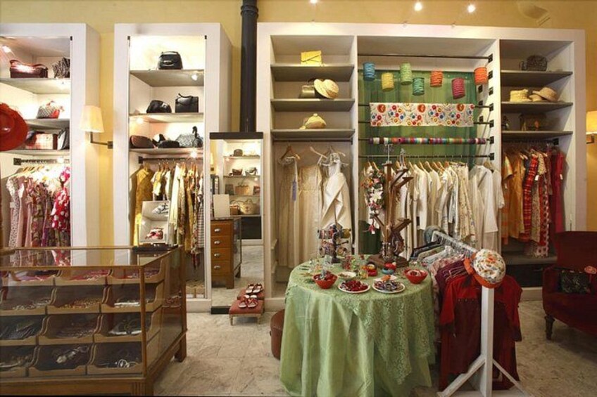 Une boutique où l’on trouve des étagères remplies de sacs à main, des portants à vêtements et une table où sont exposés des accessoires. 5
