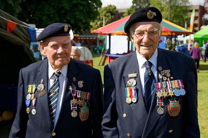 Two men in military uniforms with medals, standing outdoors at an event. 4