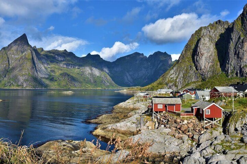 Ein Küstendorf mit roten Häusern an einem Fjord, umgeben von Bergen. 1
