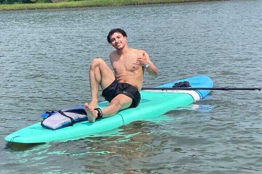 A person sitting on a green paddleboard in calm water. 5