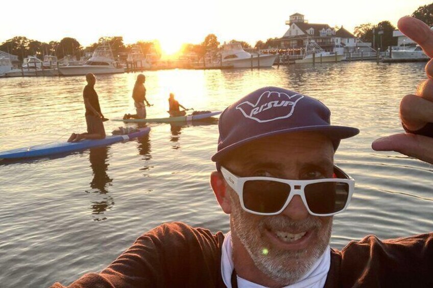 A person on a paddleboard in a body of water with boats in the background. 2