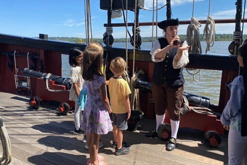 Children on a wooden deck of a ship with a person in period costume. 5