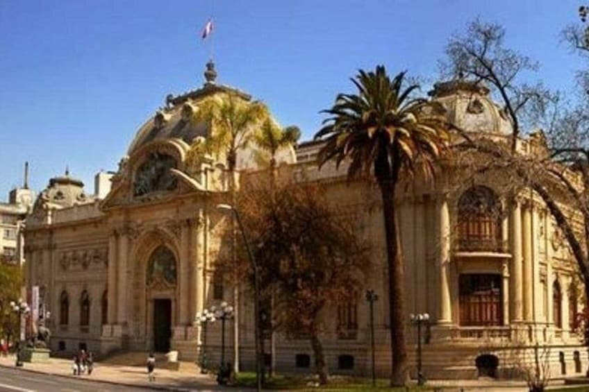 A historic building with a dome and columns, palm trees, and a clear sky. 2