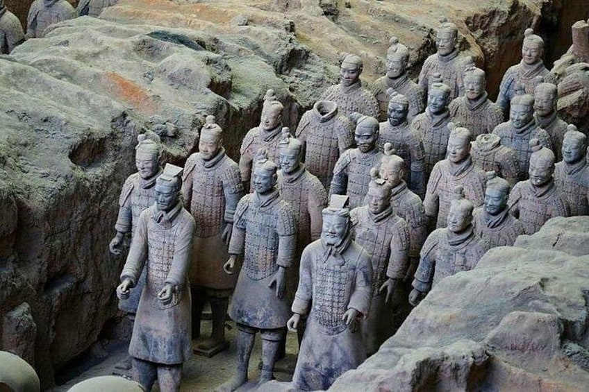 Terracottasoldaten opgesteld in een rij, staand op rotsachtig terrein. 5