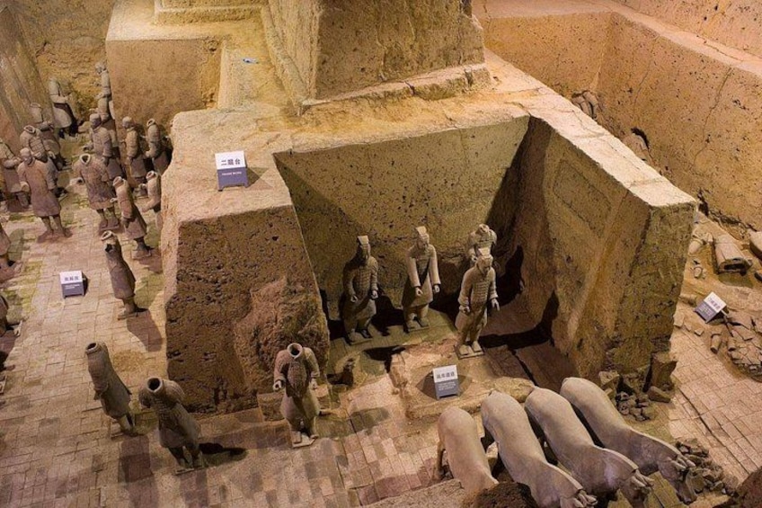 Een tentoonstelling van een terracotta leger met soldaten, wagens en een grote kuil. 3