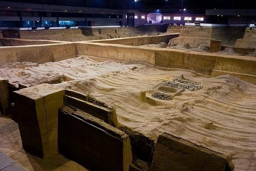 Een archeologisch terrein met blootgelegde grondlagen en stenen constructies. 4