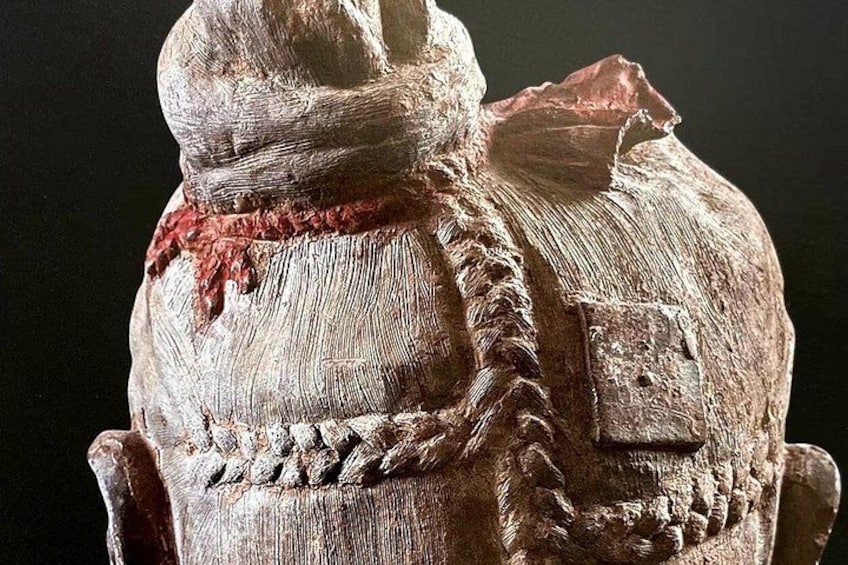 Een sculptuur met een structuurrijk oppervlak, een hoed en een rode band. 2