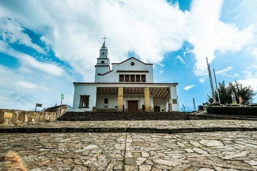 Una chiesa bianca con un campanile, gradini che conducono all'ingresso e un cielo azzurro intenso. 3