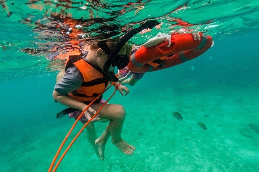 A person underwater holding a red life buoy. 2