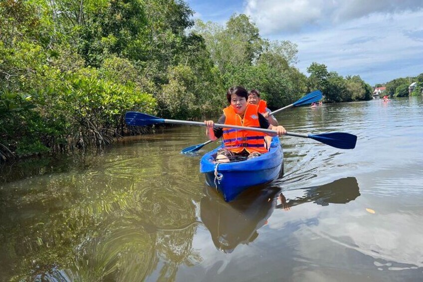 Une personne, à bord d’un kayak bleu, navigue sur une rivière paisible, entourée d’une végétation luxuriante. 3