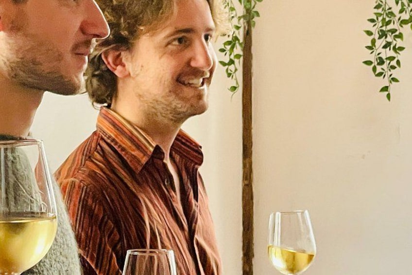 Två personer står inomhus, och en av dem håller i ett glas vitt vin. 2