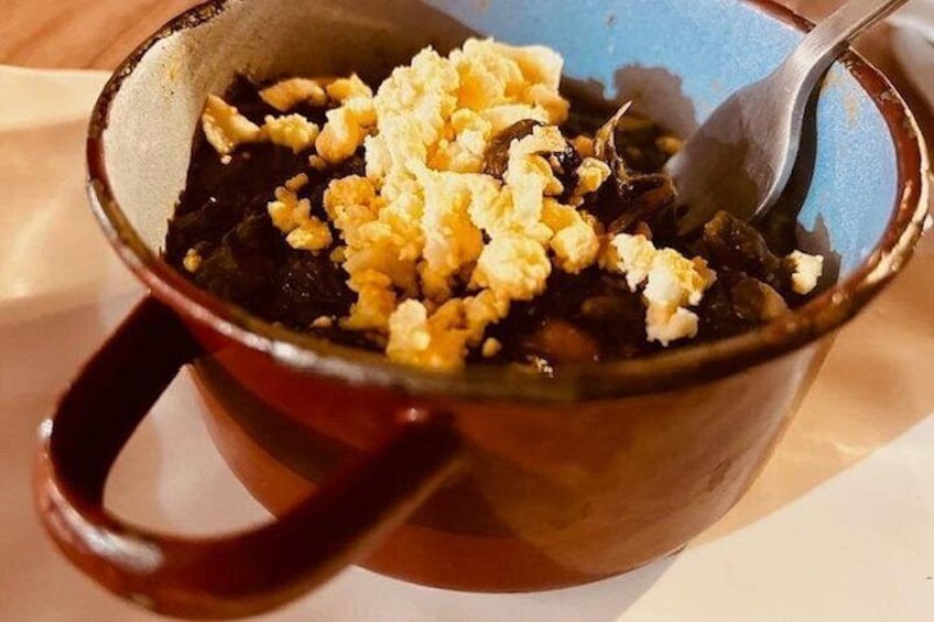 En mugg med handtag, fylld med en mörkdryck och smulad gul ost. 3