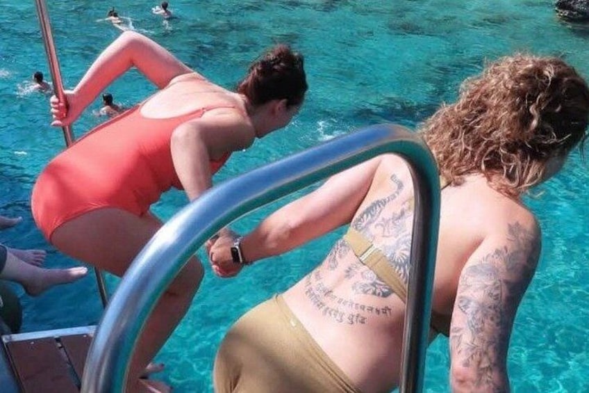 En person i badetøj står i en pool med en metalstige. 2