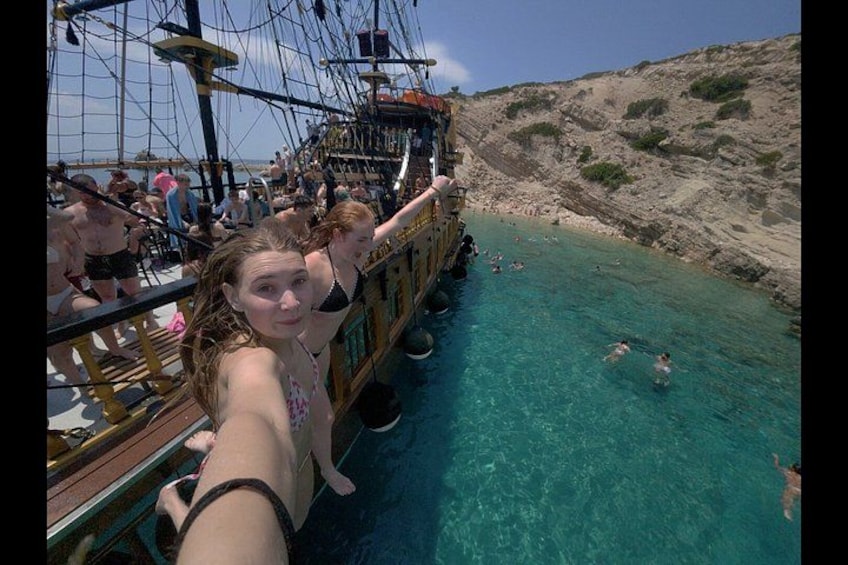 Un barco pirata con gente a bordo y nadadores en el agua. 3