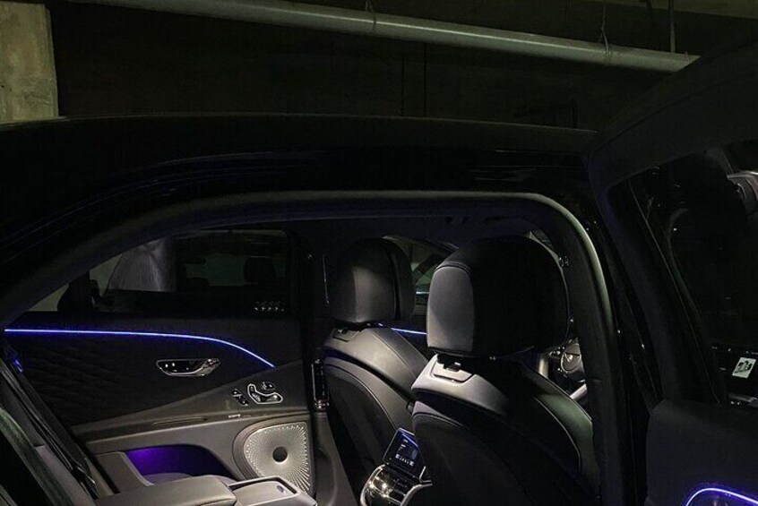 The interior of a car with a dark color scheme and blue ambient lighting. 4