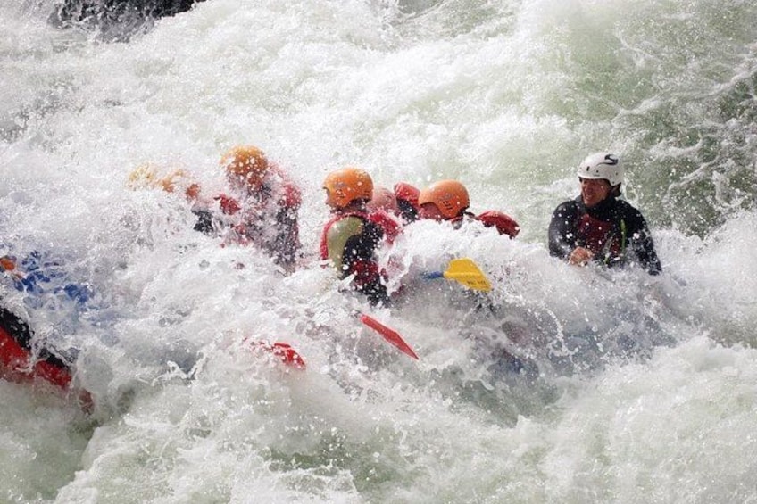 Un grupo de personas en un kayak blanco navega por rápidos turbulentos. 1